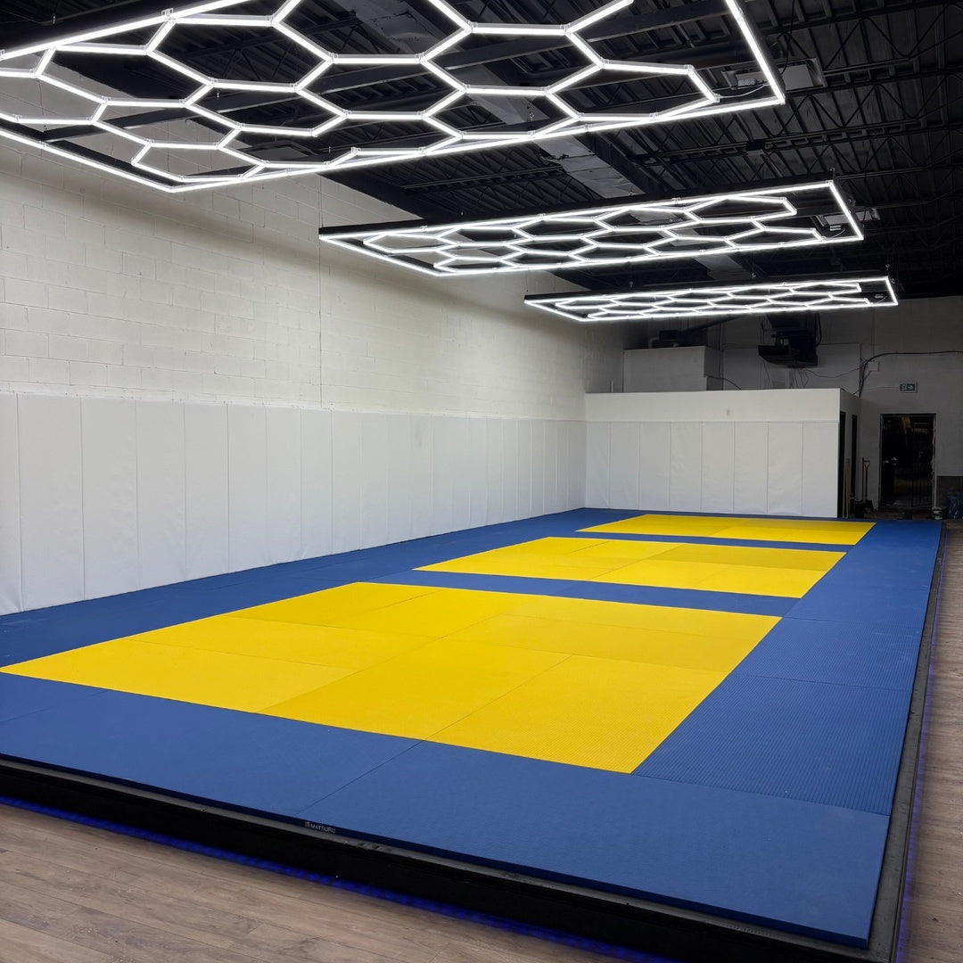 Professional martial arts academy with blue and yellow tatami mats and hexagonal LED lighting